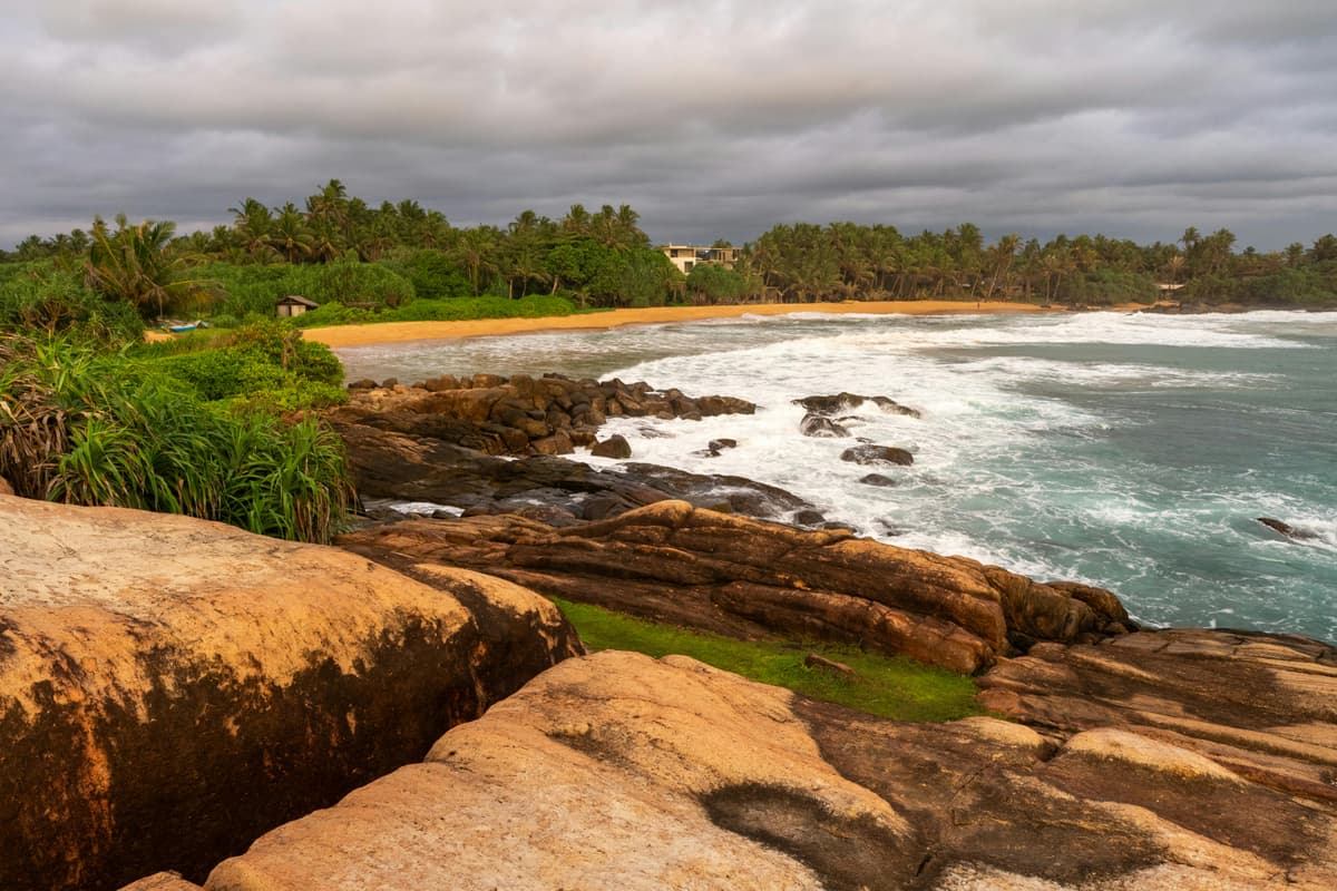 Rough surf breaking on a rocky beach under grey skies in Sri Lanka