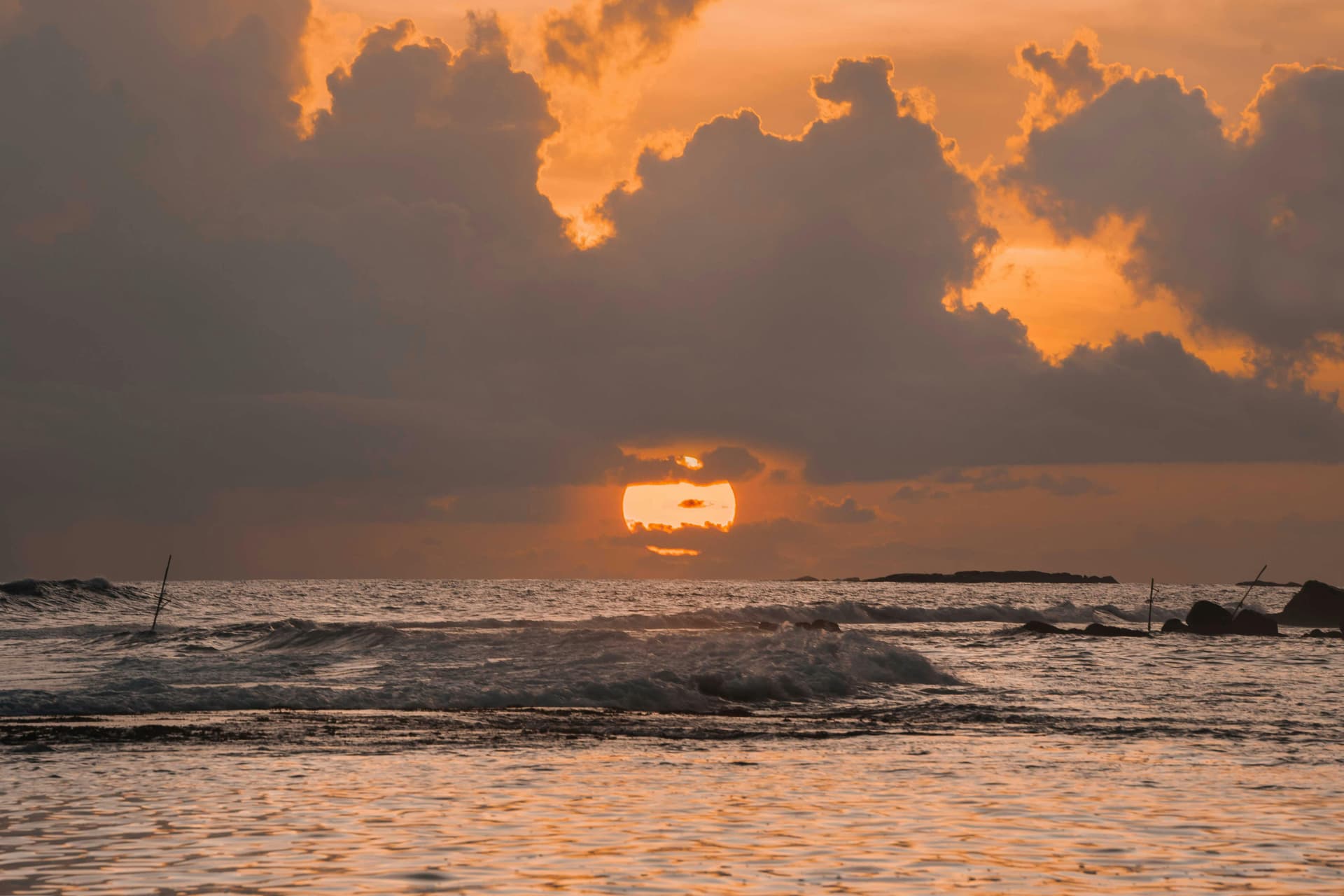 Storm clouds breaking around the setting sun over the ocean on Sri Lanka's coast