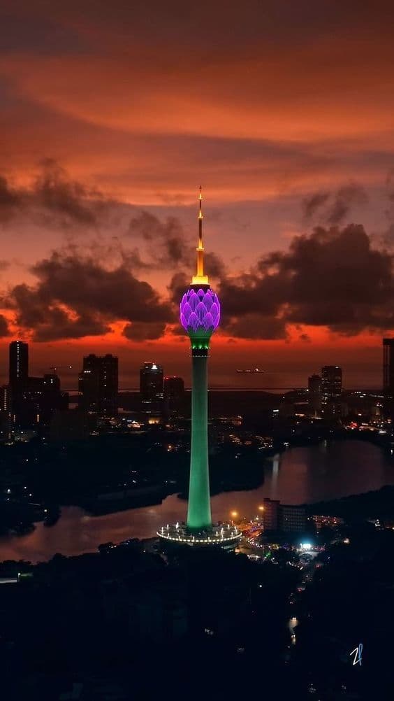 The Colombo Lotus Tower lit purple against a red sunset over the city skyline